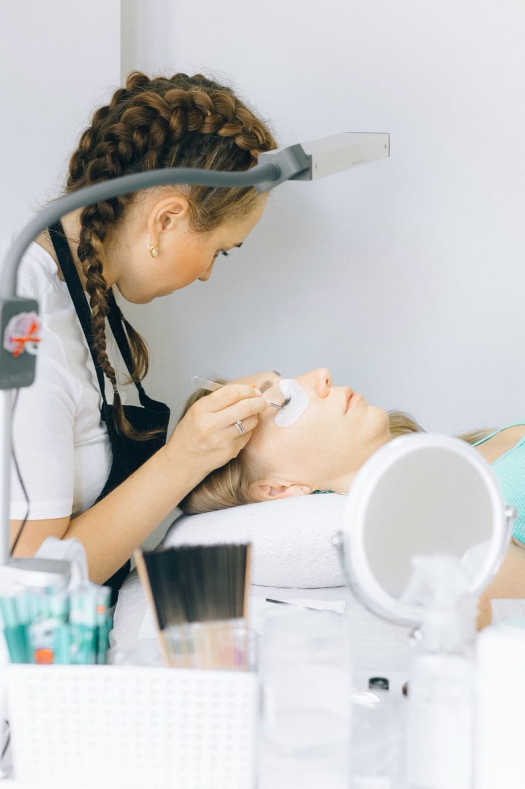 Kosmetikerin setzt einer liegenden Kundin Wimpernextensions