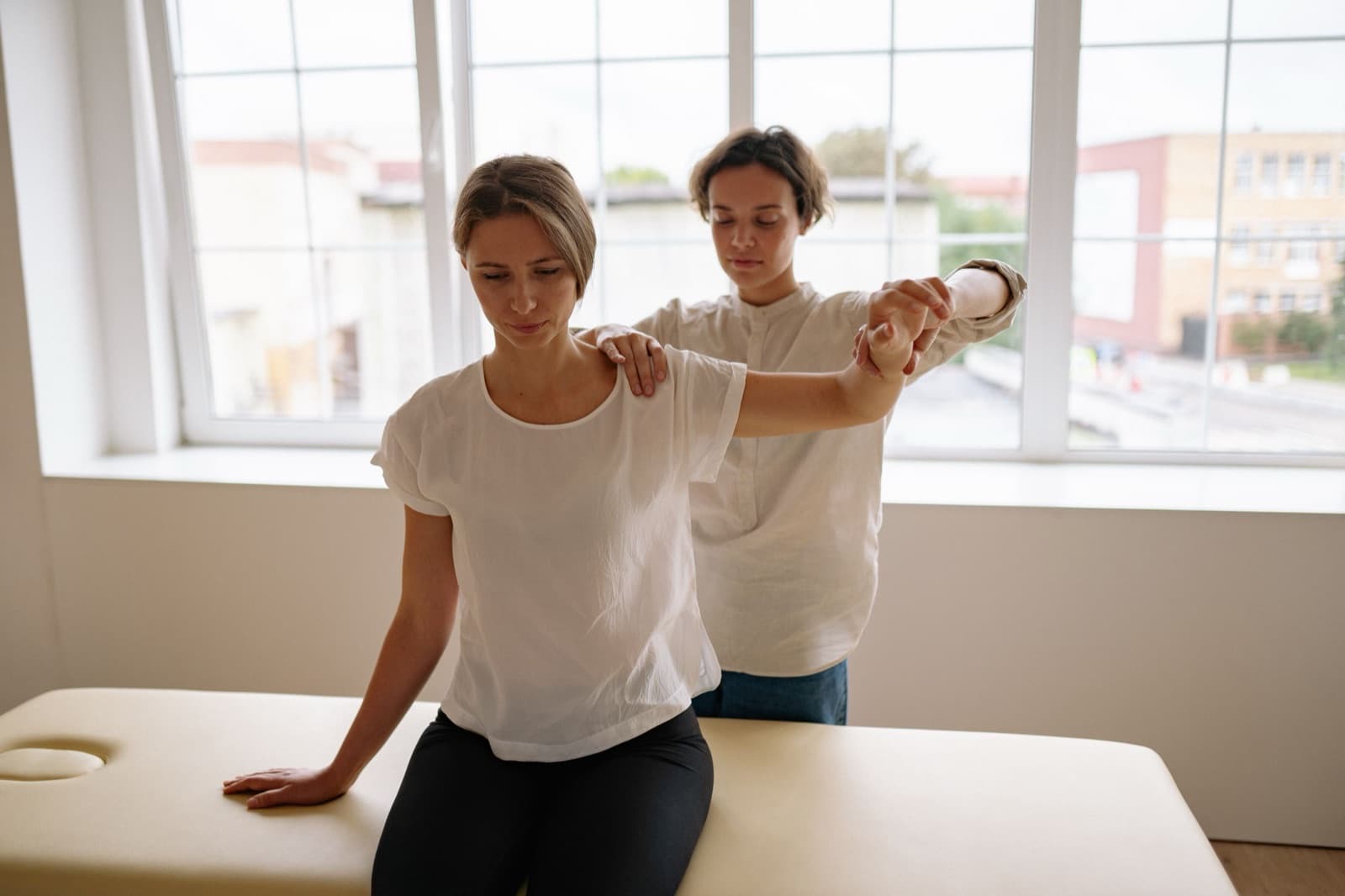 Physiotherapeutin mobilisiert Schulter und Arm einer Patientin